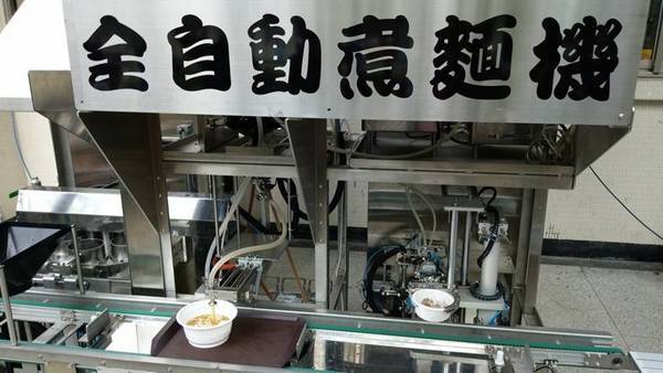 台灣科技大學發表全自動煮麵機,機器正在給湯,牛肉食材在右側準備倒入碗中。(陳國維 攝)