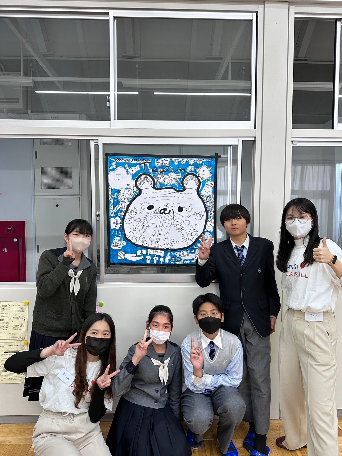 Taking a group photo with Tsuda Academy students and the SDGs collaborative artwork.